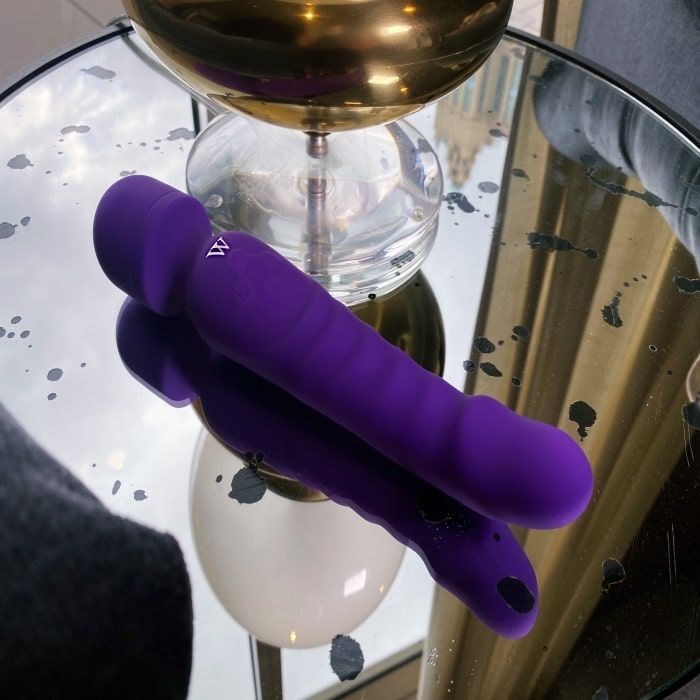 Venus flexible wand vibrator in purple resting on a reflective surface, showcasing its soft silicone design.