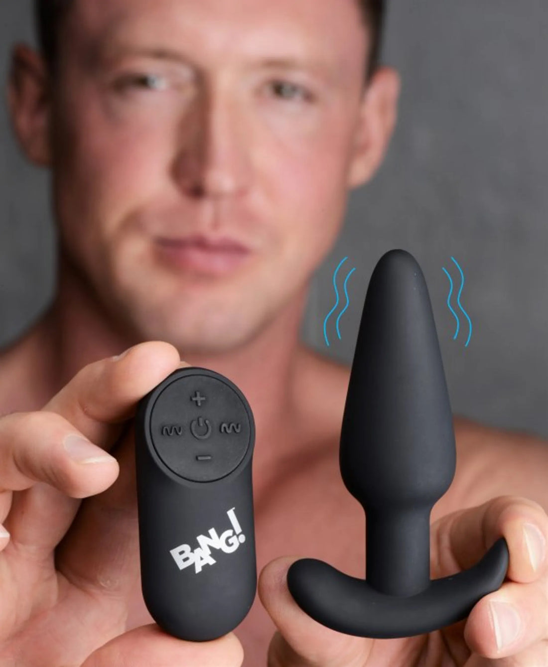 Man holding a vibrating silicone butt plug with remote, showcasing the product features and design.